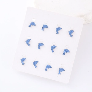 Close-up of twelve blue glitter dolphin stud earrings neatly arranged on a white card