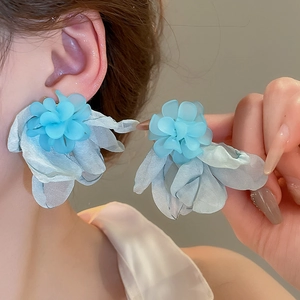 Dettaglio di orecchini a fiore in tulle blu con petali stratificati e stami fini