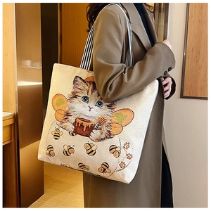 Detailed view of canvas tote bag with cute cat illustration and striped shoulder strap