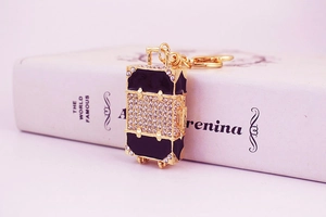 Detail of a sparkling rhinestone suitcase keychain on a vintage book background
