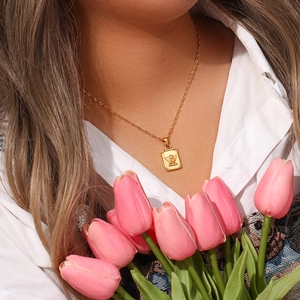 Detail of a gold angel portrait pendant necklace with zircon border worn by a model