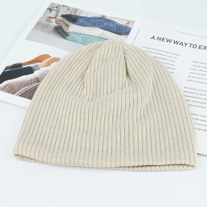 Detailed view of the creamy white knitted beanie showing soft ribbed texture on a magazine
