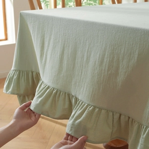 Close-up of light green cotton linen tablecloth featuring decorative lotus ruffle edges