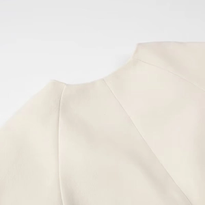 Detailed close-up of crew neckline and shoulder stitching on beige soft casual jacket