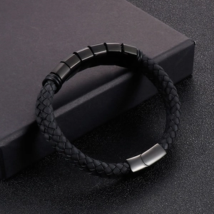 Detail of black braided leather bracelet with matte metal charms in a luxury gift box