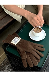 Close-up of brown wool knit gloves featuring a vintage branded woven label on the cuff