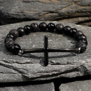 Men's gunmetal cross bracelet with black matte lava stone and agate beads on rock background