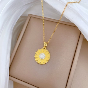 Elegant gold titanium steel necklace with a yellow enamel daisy pendant on silk fabric