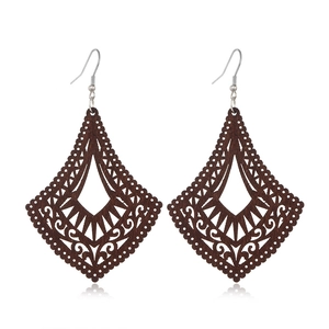 Macro shot of dark brown wooden rhombic earrings with intricate hollow-out floral patterns