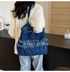 Détail du sac cabas en jean bleu avec broderie 7STREET blanche et bordures effilochées