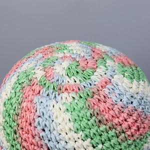 Close-up of a colorful hand-woven straw sun hat with pastel pink and blue textures