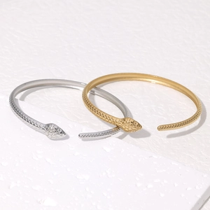 Detail shot of wavy snake texture and engraved head on gold and silver steel bangles