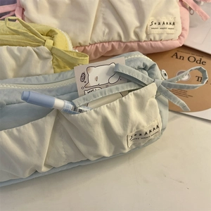 Detail of macaron fabric pencil cases with ribbon bows and multi-pocket storage design