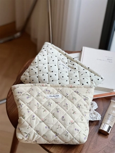 Detail of quilted corduroy cosmetic bags with heart and floral prints on a wooden table