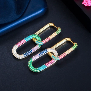Macro shot of gold-plated link earrings with multi-colored pavé zircon stones on dark background