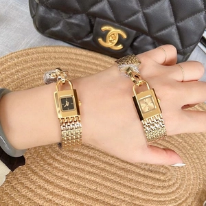 Close-up of golden padlock-shaped square watches on wrist with black and gold dials