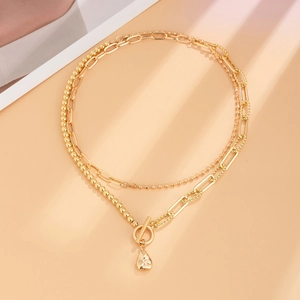 Detail of multi-layer gold chain necklace with toggle clasp and drop pendant
