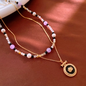 Détail d'un collier vintage à double rang avec pendentif rose et perles multicolores