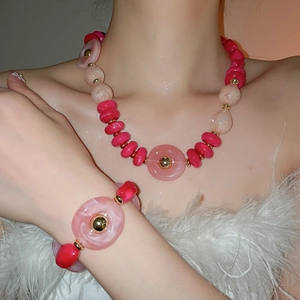 Close-up of vibrant pink acrylic chunky bead necklace and bracelet set on model
