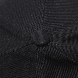Makro-Detail einer schwarzen Baseballkappe mit stoffbezogenem Knopf und Nähten oben