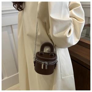 Détail du mini sac cylindrique marron foncé avec bandoulière chaîne et poignée supérieure