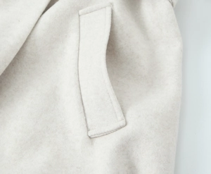 Close-up of high-quality plush fabric texture and stitching on beige hooded wool coat