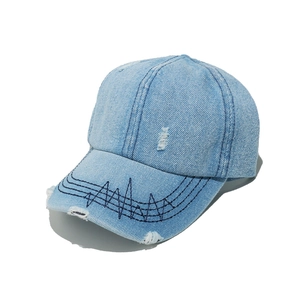 Detail showing distressed light blue denim baseball cap with frayed holes and wave stitching