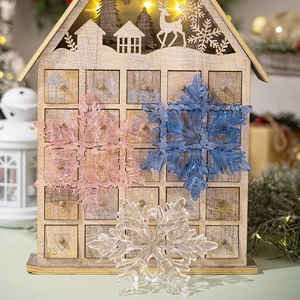 Detail of pink and blue acrylic snowflake ornaments hanging with warm festive lighting