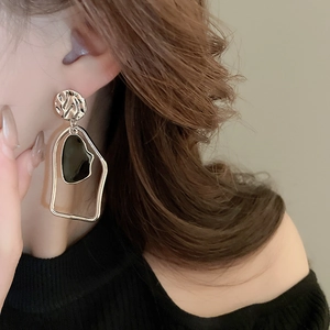 Vue détaillée des boucles d'oreilles géométriques irrégulières dorées avec insert noir