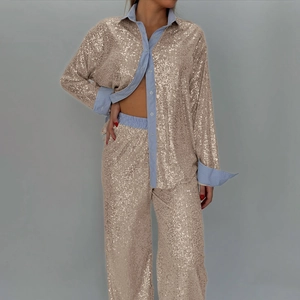Detail of champagne gold sequin suit with striped cuffs and wide-leg trouser texture