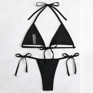 Black lace-up bikini set with triangle top and side-tie bottoms on marble background