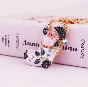 Golden Santa boot keychain with green crystals on a vintage book background