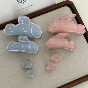 Flat lay of blue and pink dolphin-shaped resin hair claws in various sizes on a tray