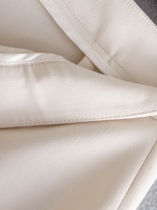 Macro detail showing refined stitching and premium fabric texture of beige trousers