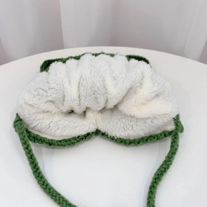 Detail showing the thick white fleece lining and green knitted wool of the baby earflap hat