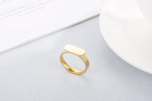 Detailed view of a gold square signet ring with a minimalist flat top on a soft background