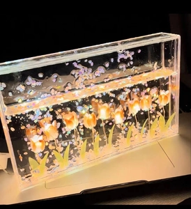 Macro shot of rectangular acrylic night light with glowing orange tulips and glitter