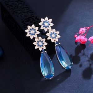 Detail of elegant blue water drop earrings with flower accents and sapphire crystals