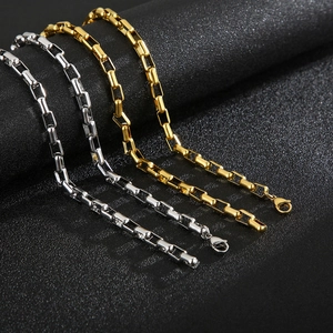 Minimalist gold and silver square box chain necklace set on a dark textured background