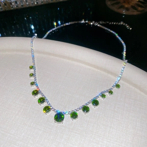 Detail of silver necklace with green round gemstones and sparkling zircon fringe design