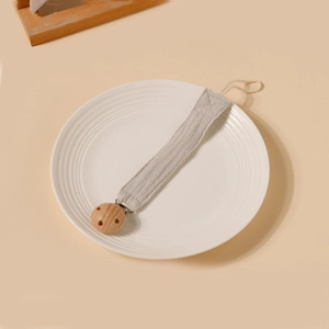 Détail de l'attache-tétine en coton gris avec clip de fixation en bois de hêtre naturel