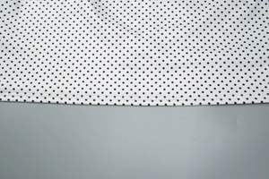 Dettaglio del tessuto bianco a pois neri con cuciture rifinite sul bordo del vestito