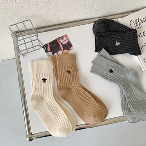 Detailed embroidery of small bee icon on vertical ribbed cotton mid-calf socks