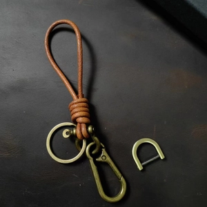 Close-up of brown braided leather keychain with brass metal ring and D-ring buckle