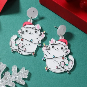 Detailed close-up of white acrylic cat earrings with red Christmas hats and festive lights