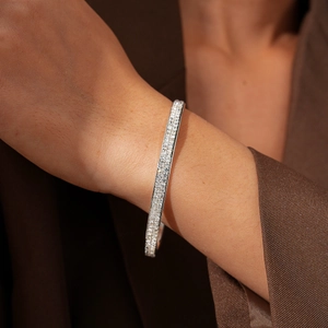 Close-up of a silver-toned geometric bangle with full pavé diamonds on a model's wrist