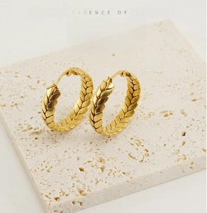 Detail of 18K gold stainless steel hoop earrings with wheat ear texture on white stone