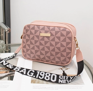 Close-up of pink camera bag with geometric pattern and wide contrast logo strap
