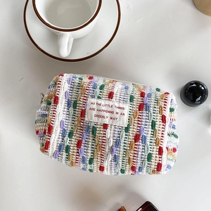Macro shot of colorful knit makeup bag featuring a top zipper and a woven fabric label
