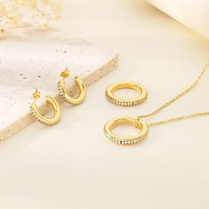 Detailed set of gold circular jewelry with rhinestones on a minimalist stone surface